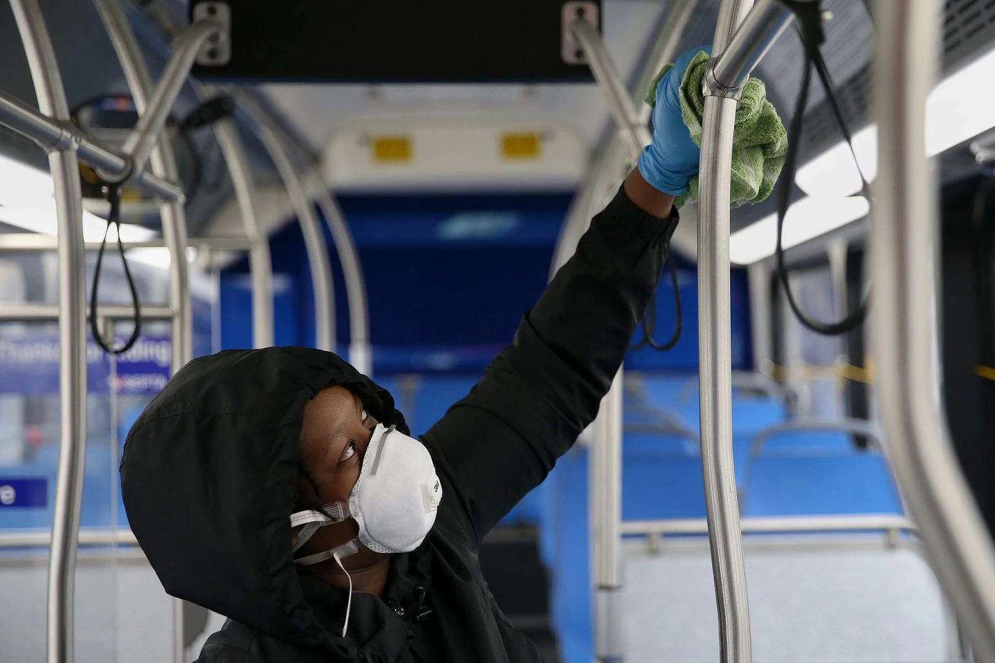 woman in mask cleans inside of a bus