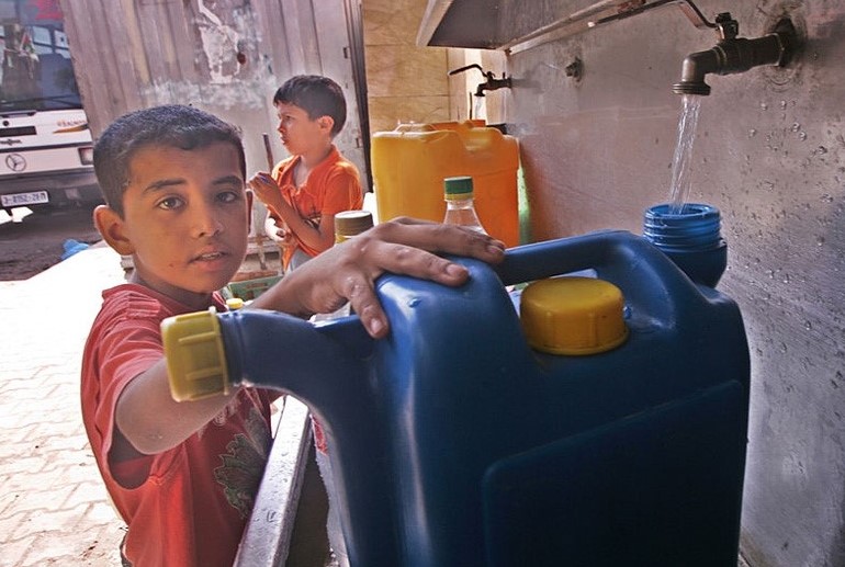 Palestinian children filling plastic water jug