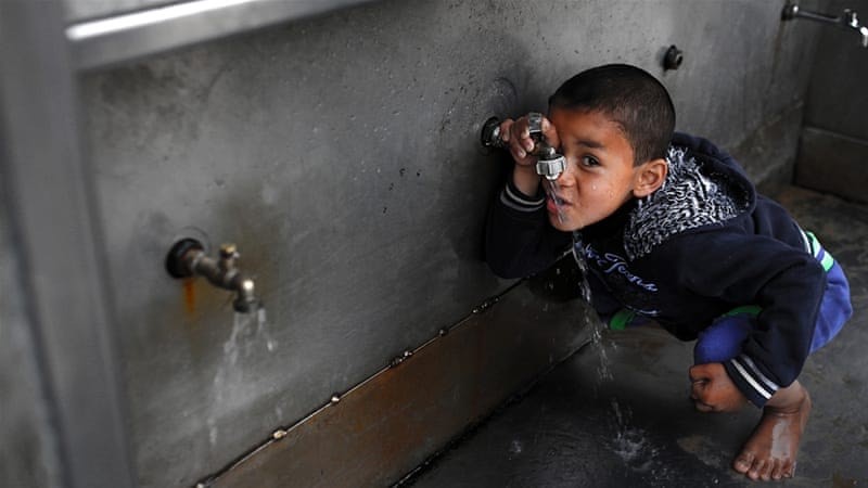 child drinking water at outdoor tap