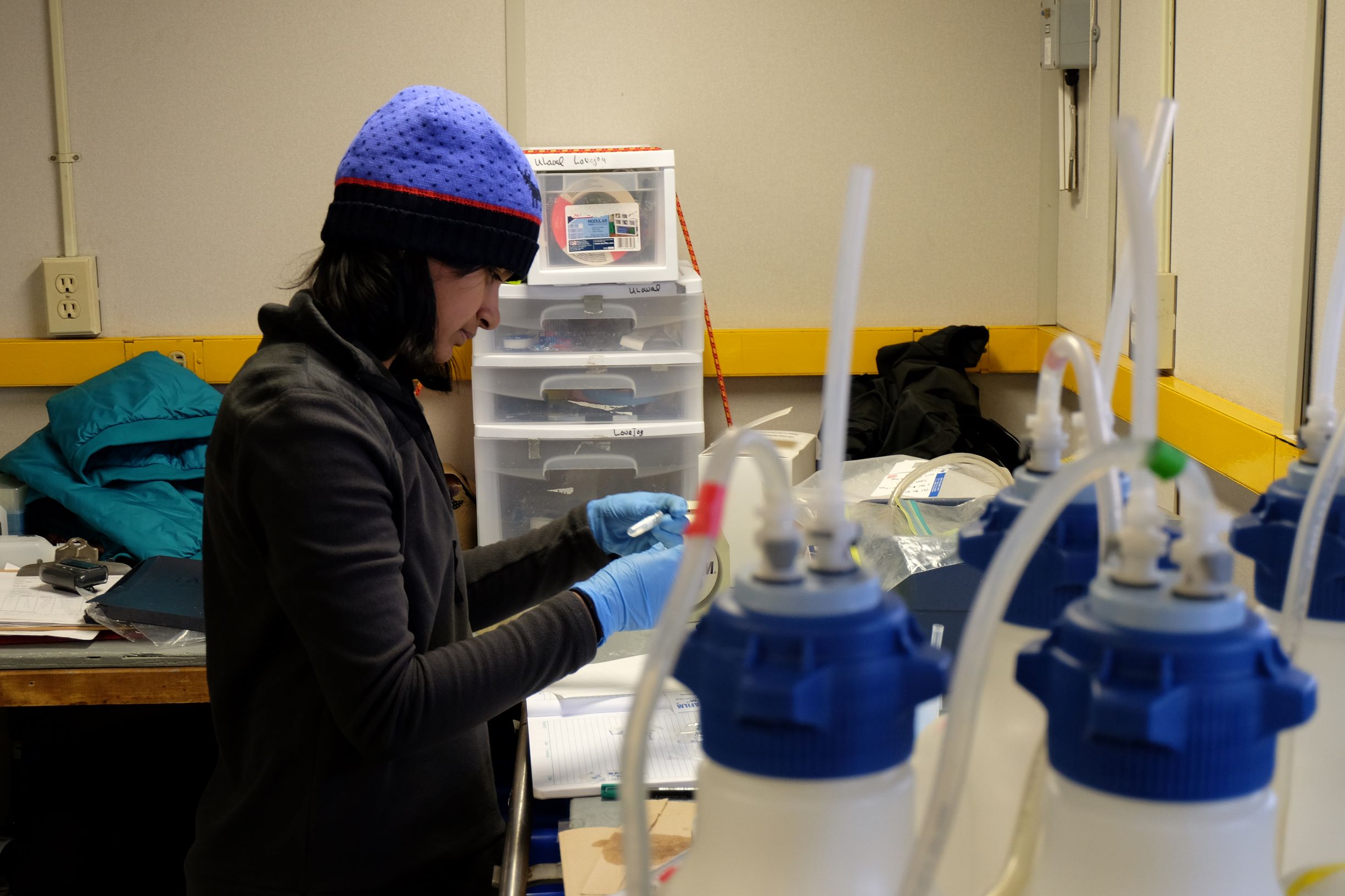 Author in wool hat and rubber gloves holds test sample in a lab