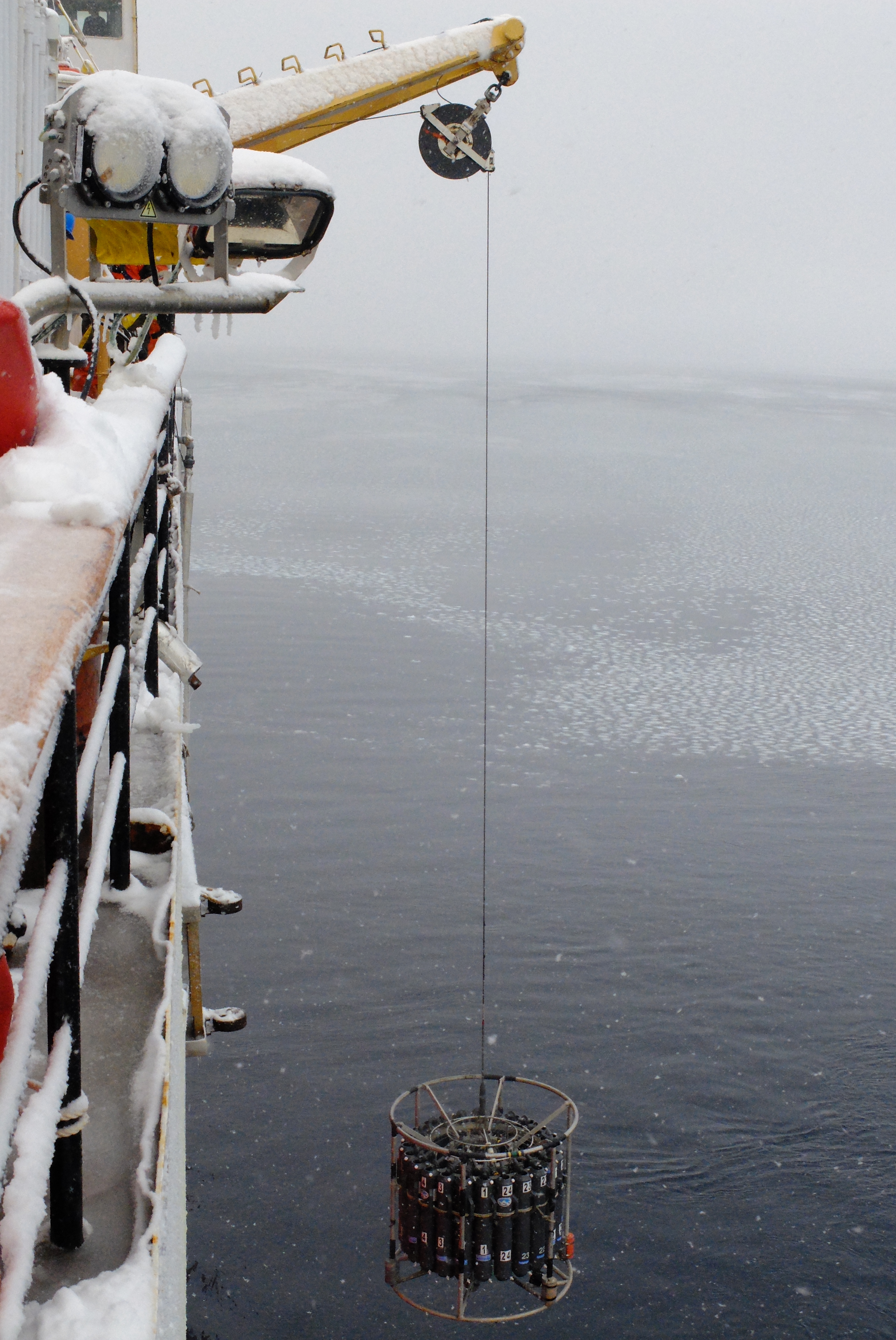 water sampling equipment suspended over the icy water from the ship