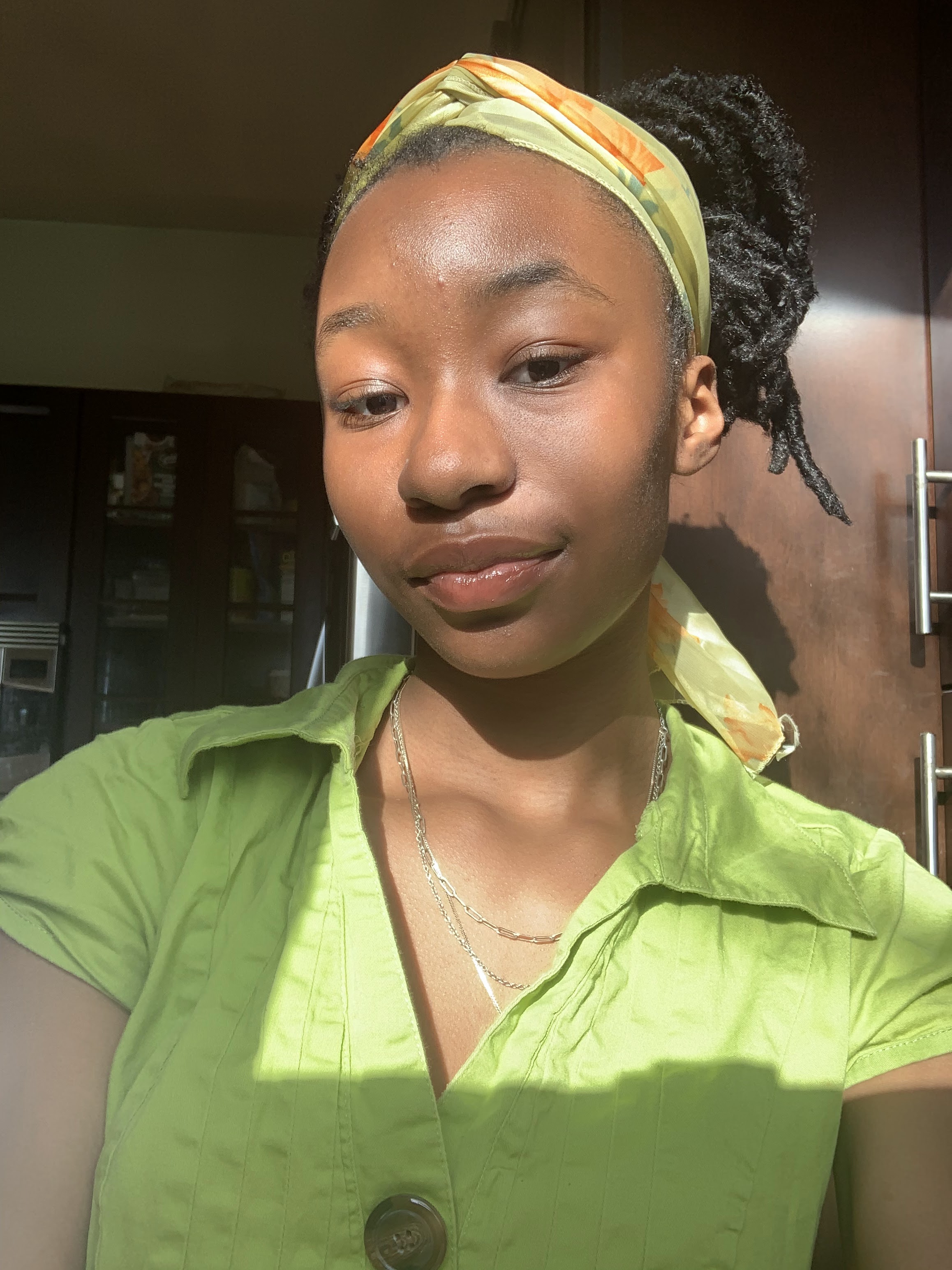 Tori smiles while wearing a bright green button down shirt and green headband with her hair pulled back.