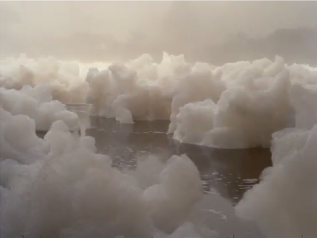 Film still of white foam floating on the river.