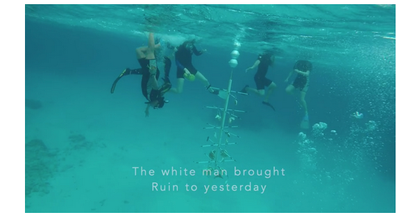 Four divers in fins in aqua blue water