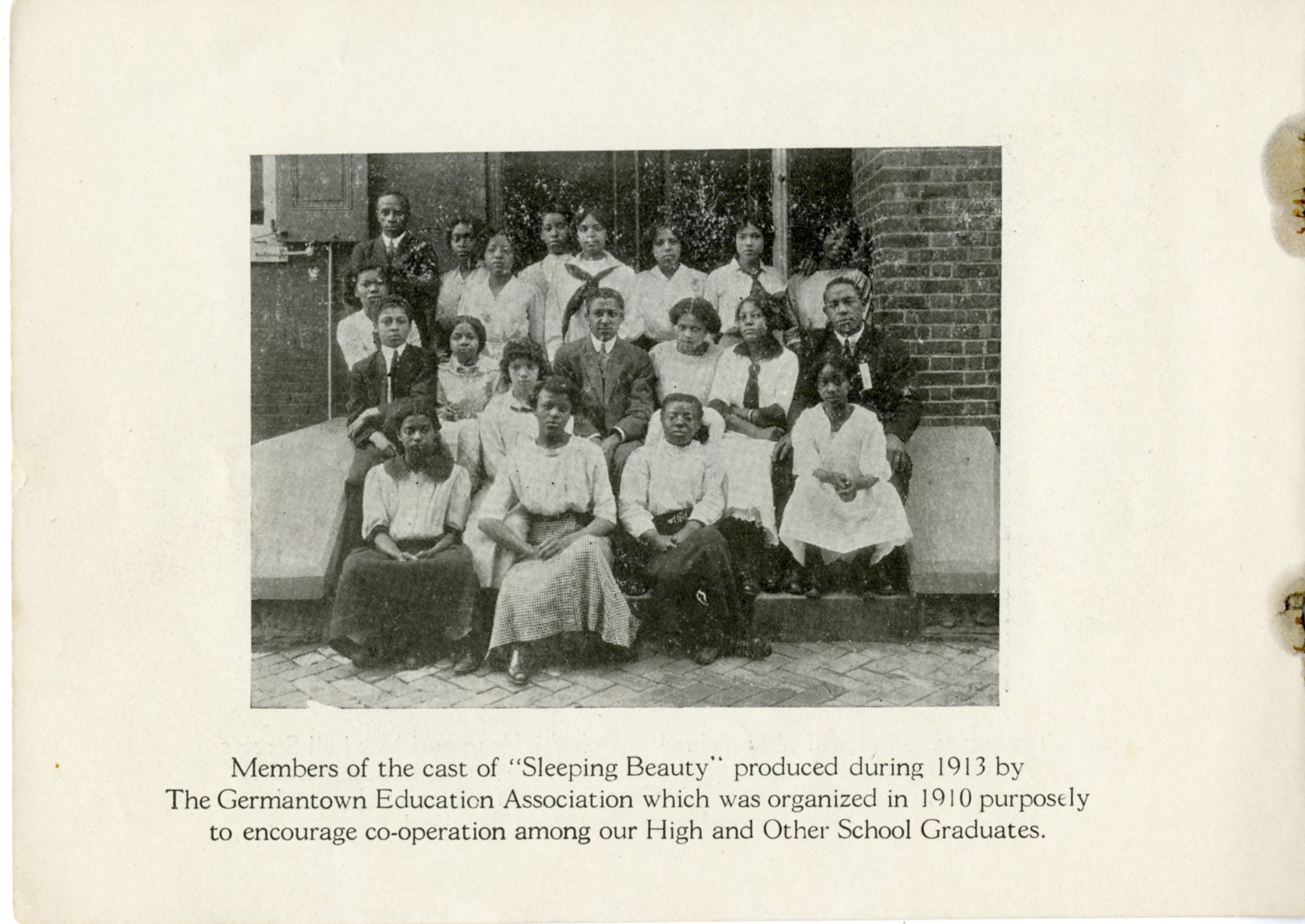 Young Black students pose for a group photo on the steps of a brick building