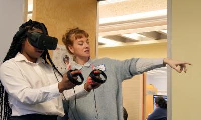 April Anson instructs a participant on using the VR headset and controls
