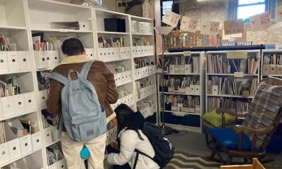 Two people stand with their back to the camera, looking at shelves of zines