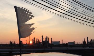 tattered US flag flying over the refinery at sunset