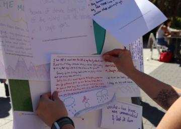 A participant adds a handwritten story to a board with other stories.